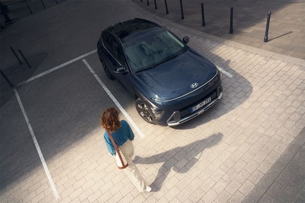 Ein parkender Hyundai KONA auf den eine Frau zuläuft