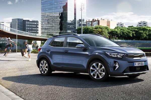 Ein Kia Stonic parkt vor einer Stadt, hinter dem Auto skaten Jugendliche